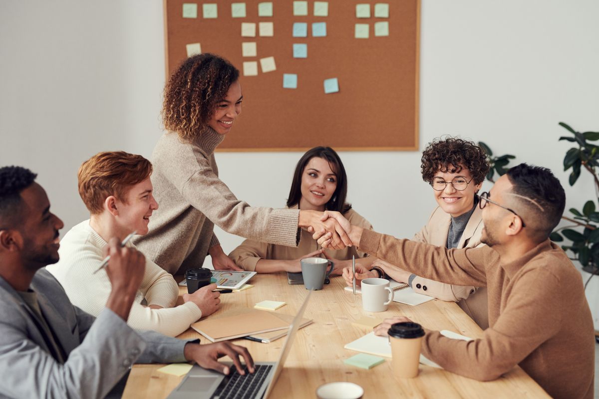 Two people shaking hands across a table in a bright office — the partnership model behind Previously's affiliate links