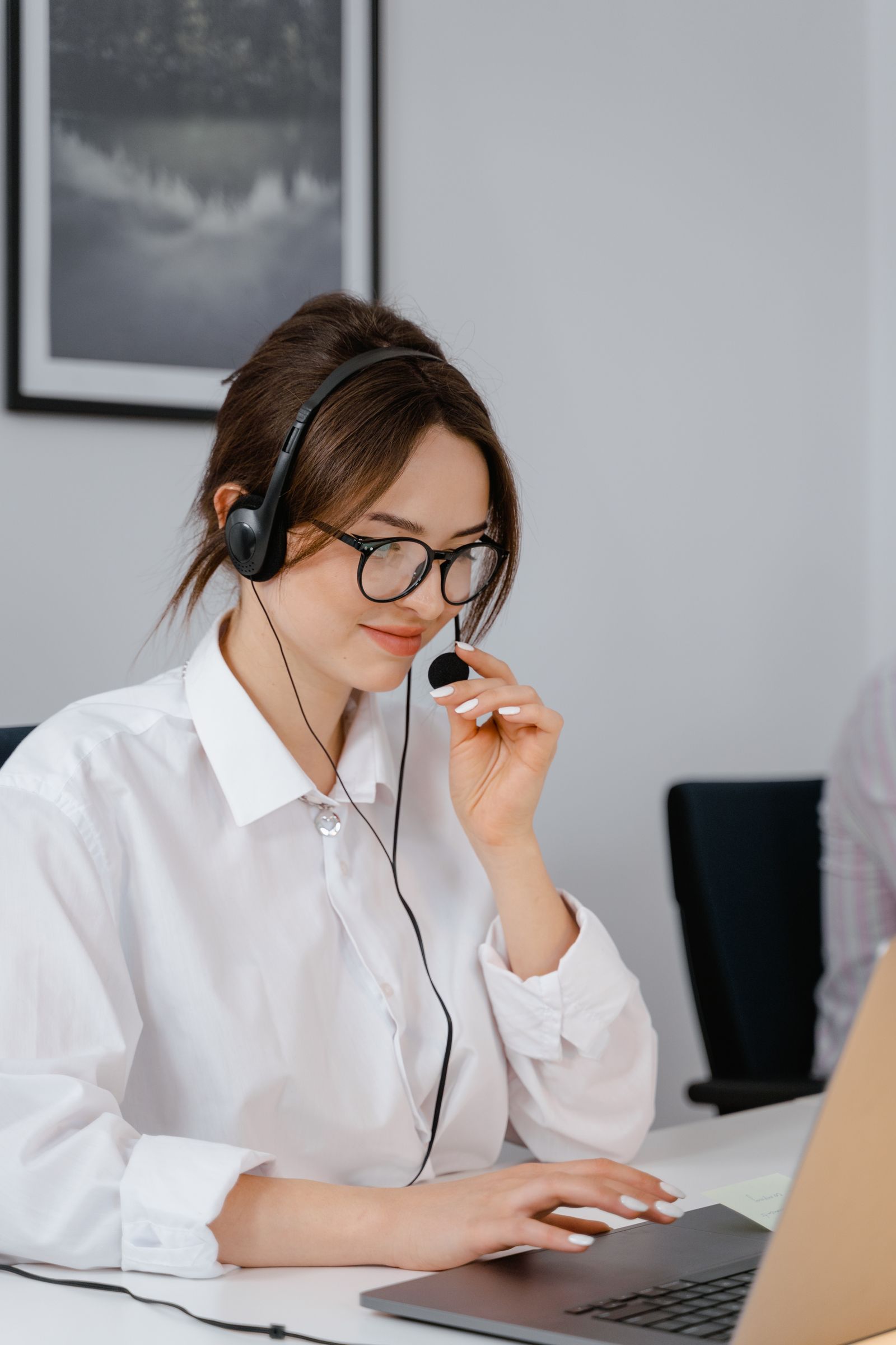 A support specialist with a headset helping a customer on her laptop