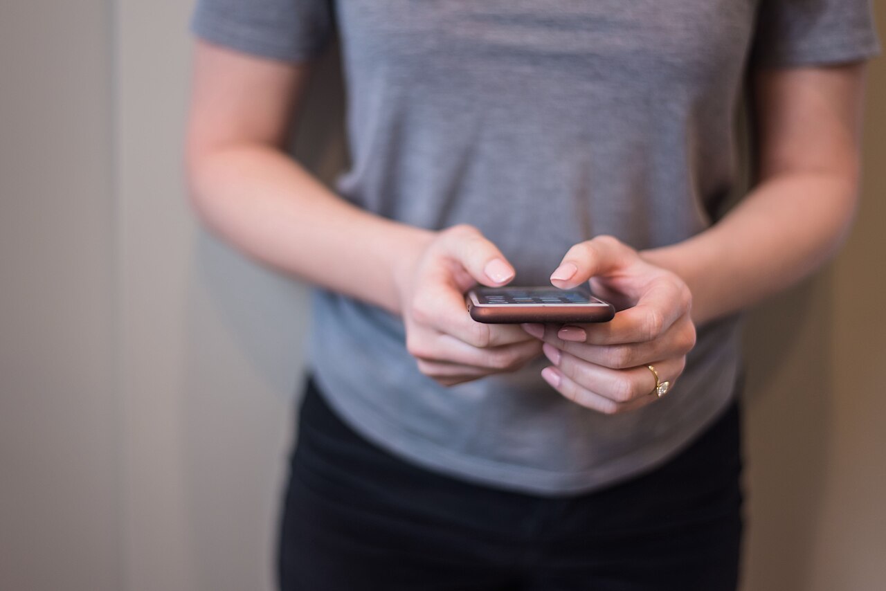 A smartphone held in a hand in bright daylight