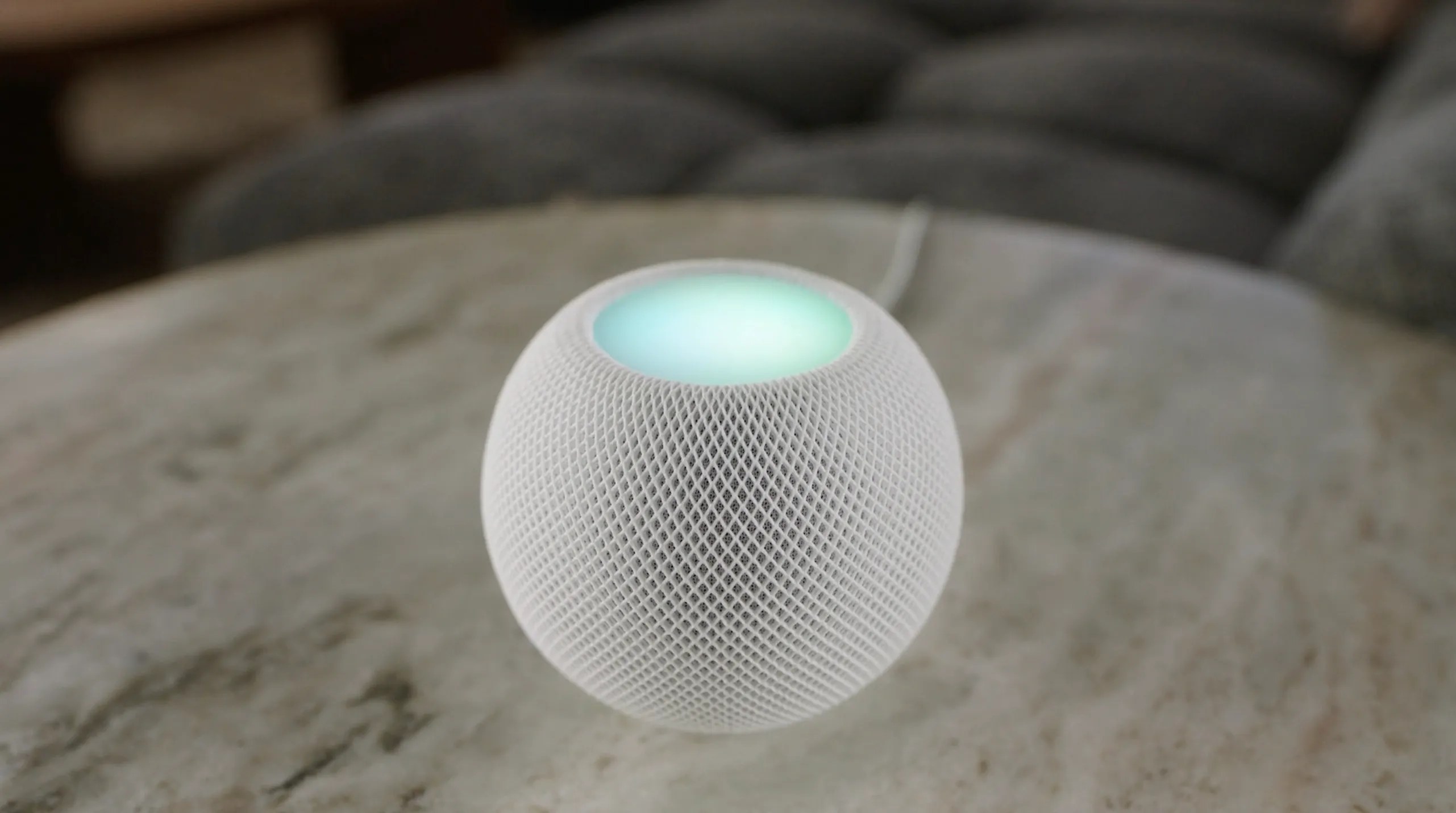 A HomePod mini smart speaker with Siri glowing on top