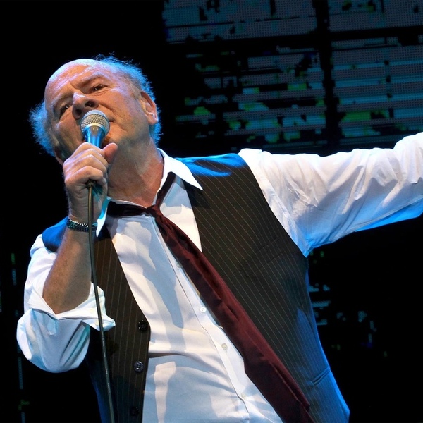 Art Garfunkel performing on stage in his signature white shirt and dark vest (press photo)