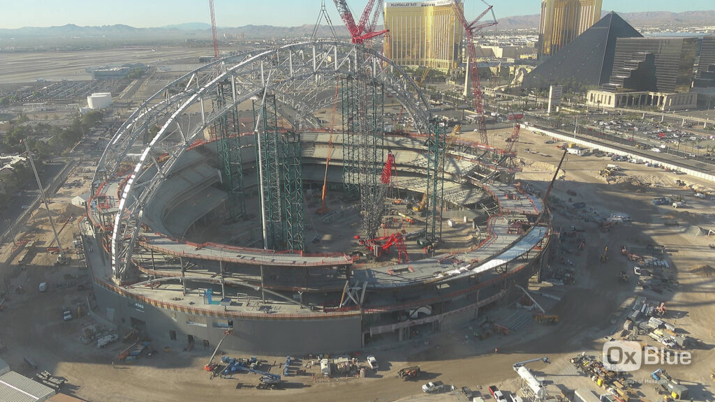 Steel truss arches rising over the Athletics' Las Vegas ballpark construction site on the old Tropicana footprint, with cranes at work