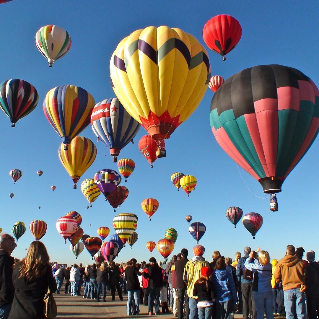 Spectators watch colorful balloons rise during the mass ascension at the Albuquerque International Balloon Fiesta