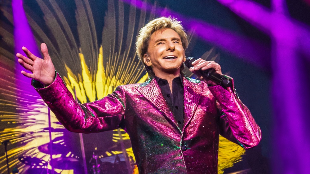 Barry Manilow performing on stage in a sparkling magenta jacket