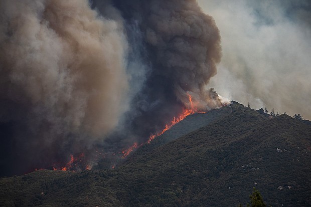 Flames and a smoke column rise over a California ridgeline during a 2024 wildfire (file photo)