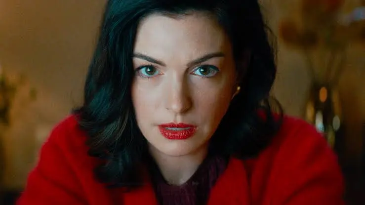 Close-up of Anne Hathaway in Verity, in a red coat, staring intently