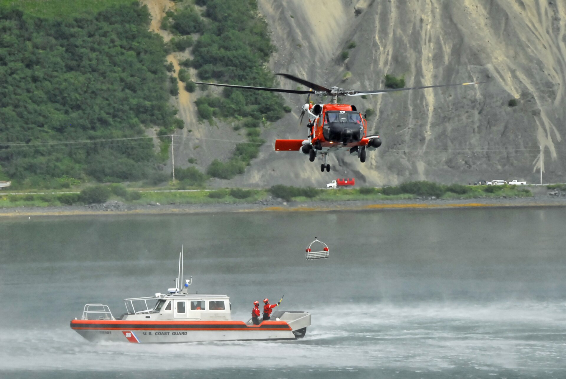 A Coast Guard MH-60 Jayhawk helicopter crew conducts a hoist demonstration over the water