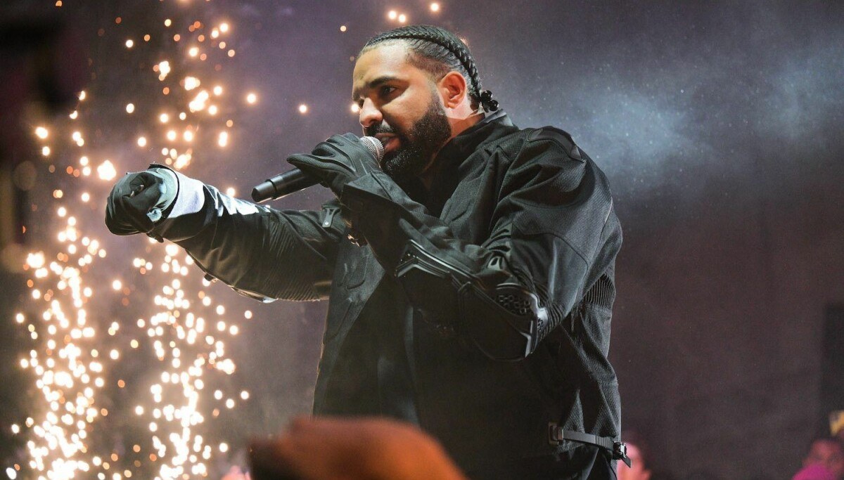 Drake performing on stage during a concert, bathed in stage light