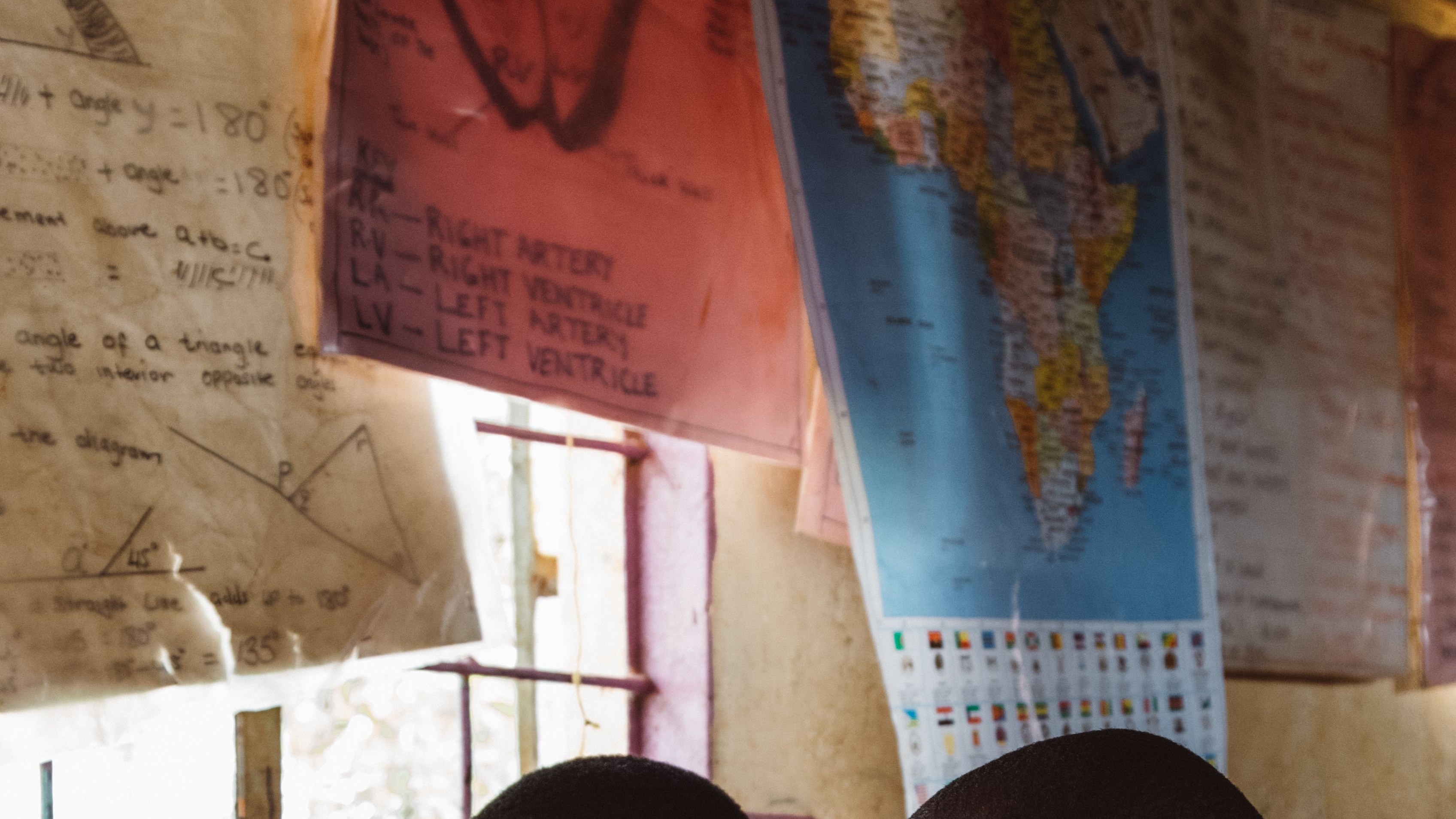 Two students studying a laptop screen in a classroom