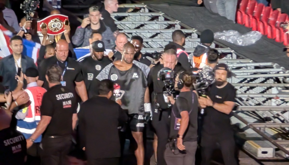 Daniel Dubois walking to the ring with his team, a championship belt held behind him