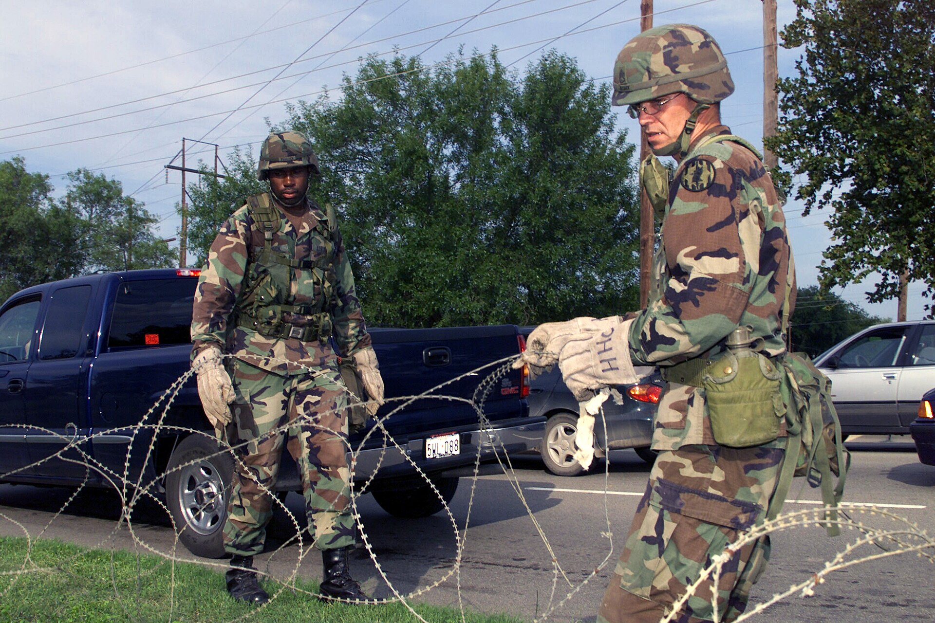 Two soldiers in camouflage placing concertina wire at the Main Gate Entrance at Fort Hood, Texas