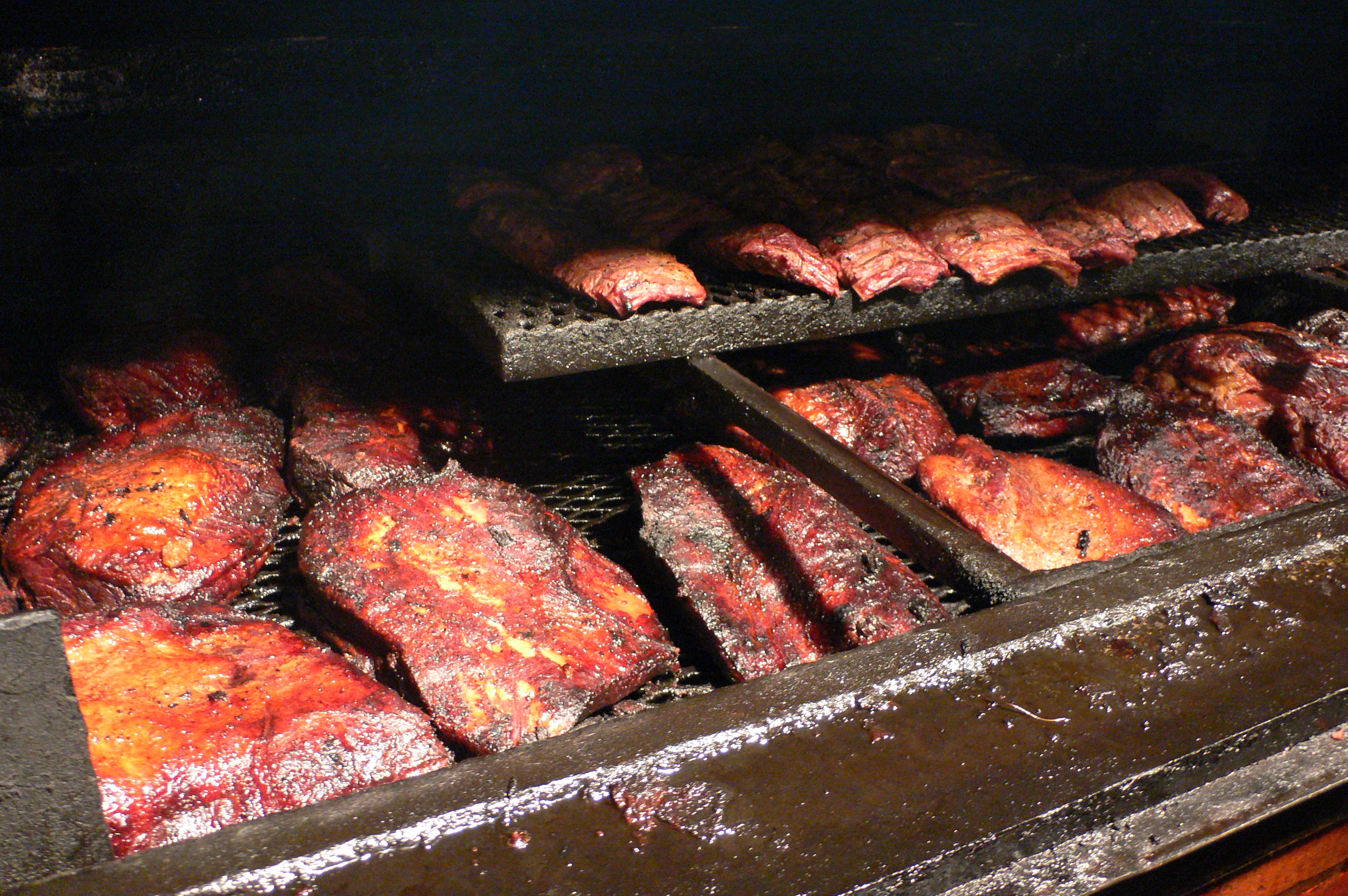 Brisket and ribs smoking on a barbecue pit, in the Texas barbecue tradition arriving in Paris