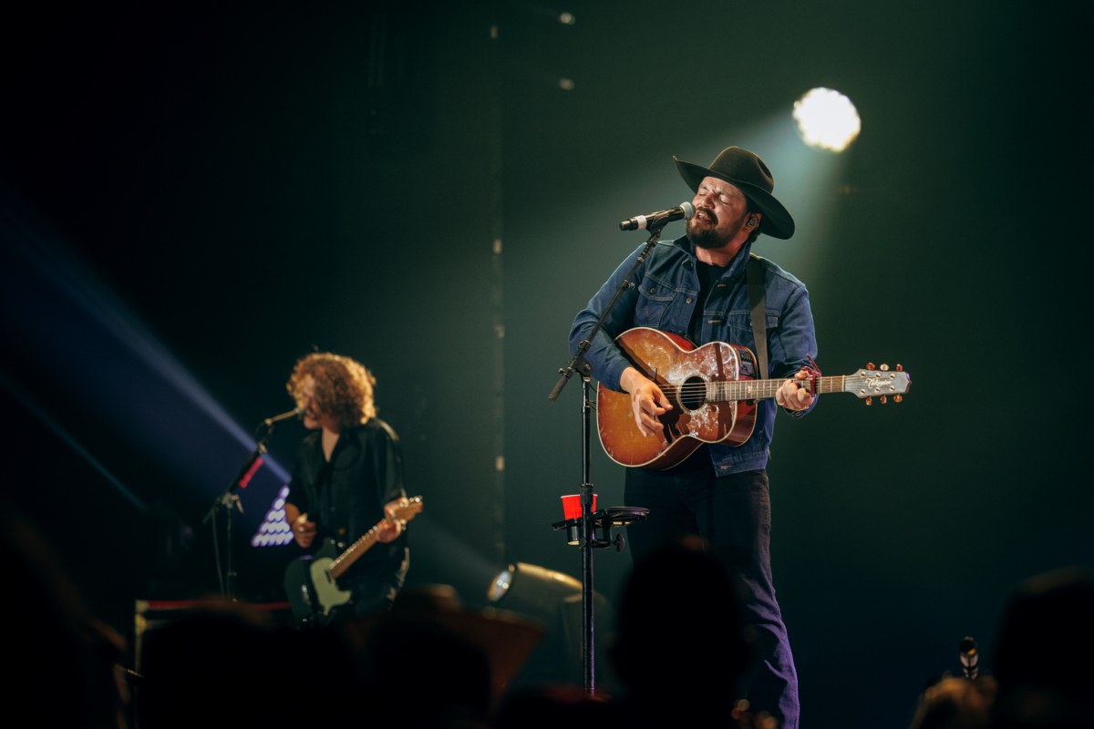 A country singer performing under a spotlight with an acoustic guitar on a concert stage