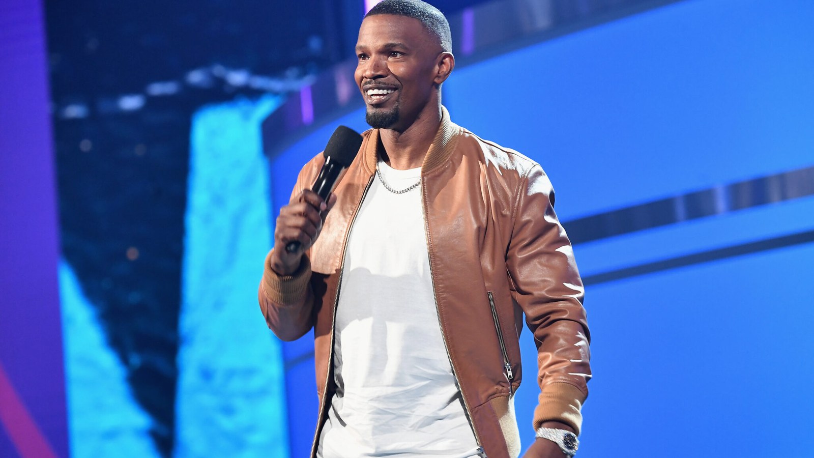 Jamie Foxx onstage with a microphone at a live performance