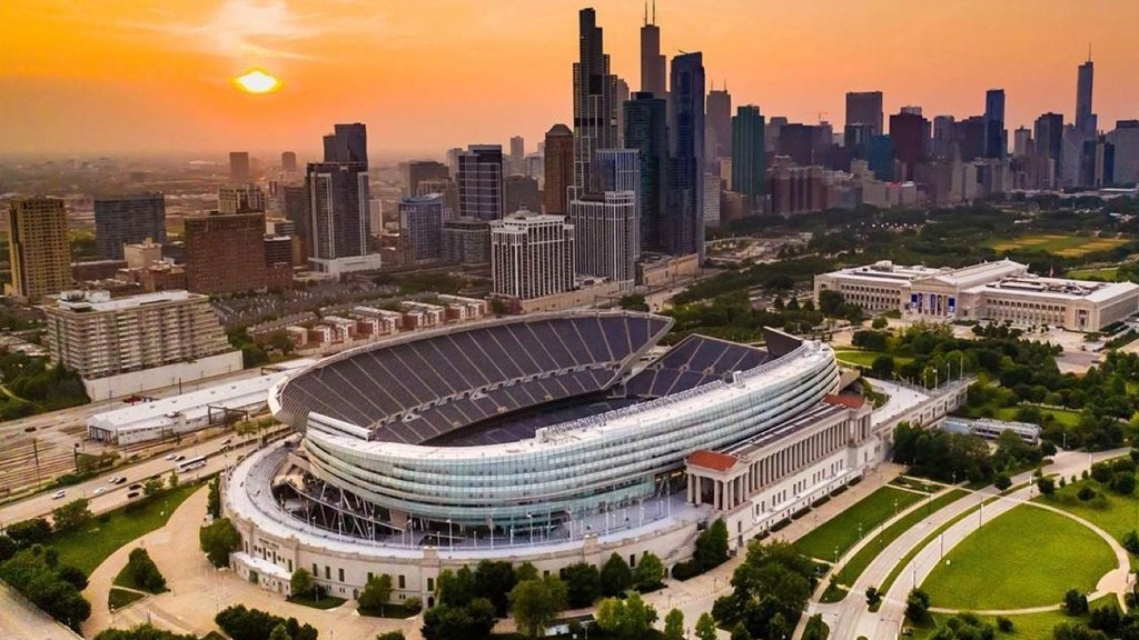 Soldier Field glowing at sunset with the Chicago skyline behind it.