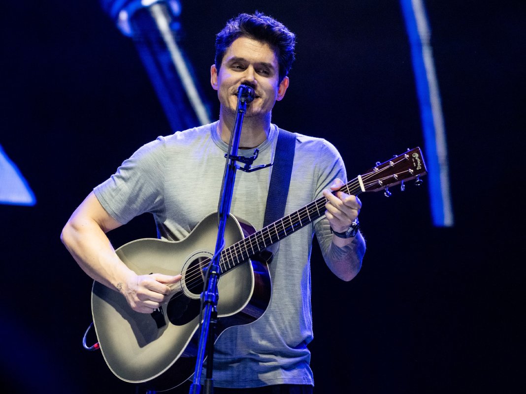 John Mayer playing acoustic guitar and singing on stage
