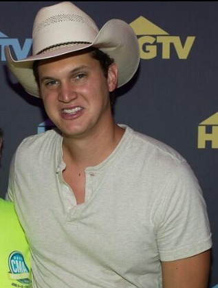 Jon Pardi in 2014, wearing a cowboy hat and a white henley shirt, smiling at an event