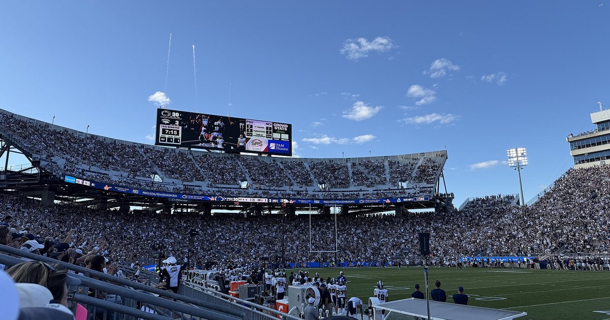 Flares rise over a packed Beaver Stadium after a touchdown on a bright college football Saturday