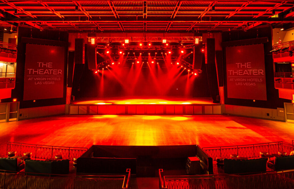 The Theater at Virgin Hotels Las Vegas lit in red with venue banners on both sides of the stage
