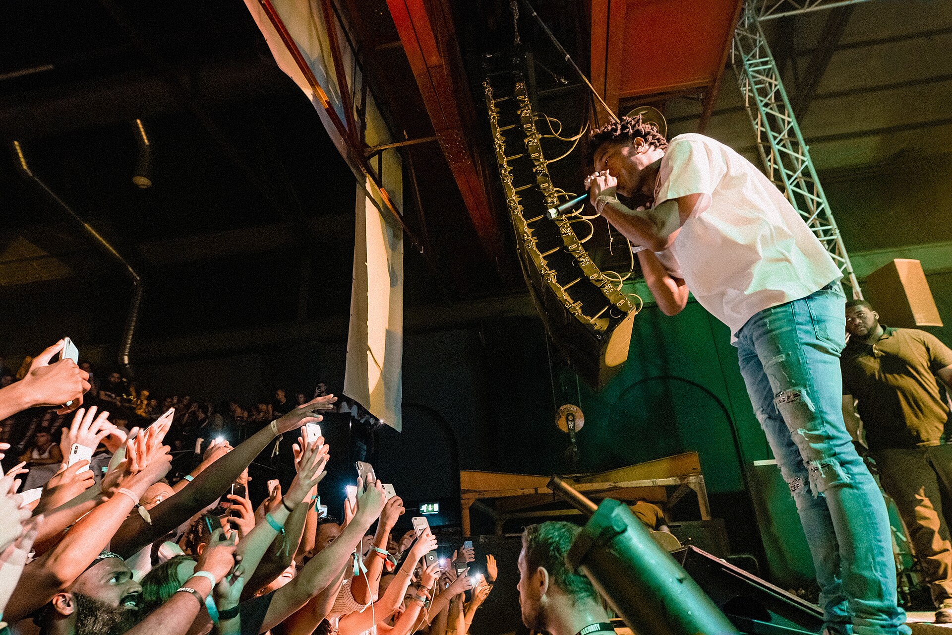Lil Baby performing live at the HYPE Festival in Oberhausen, leaning over the stage toward the crowd with a microphone in hand