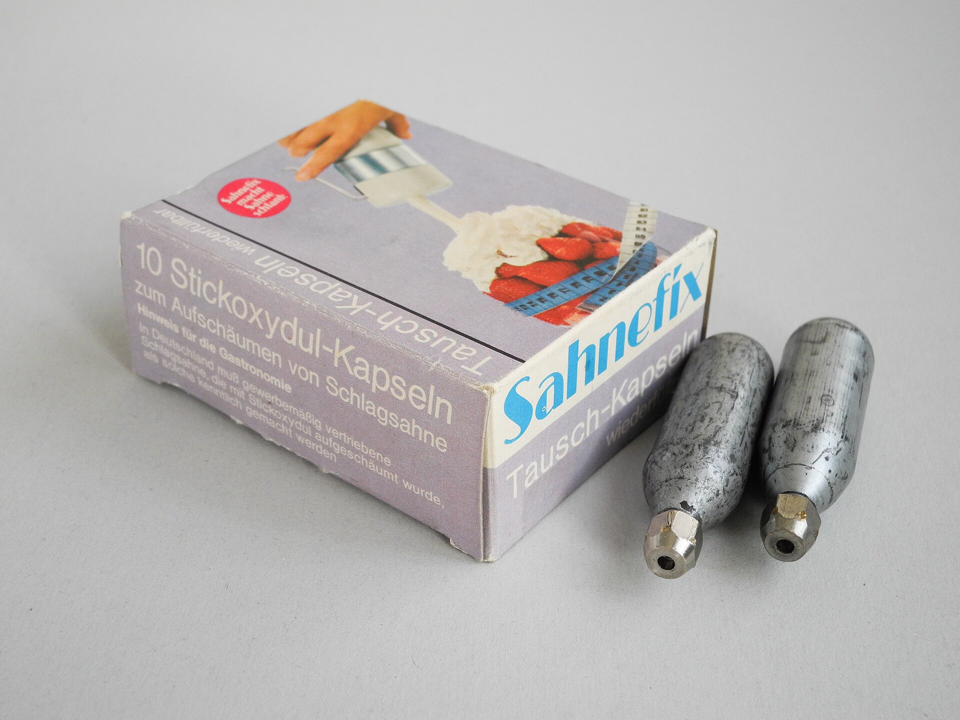 Nitrous oxide charger canisters beside a whipped-cream product box