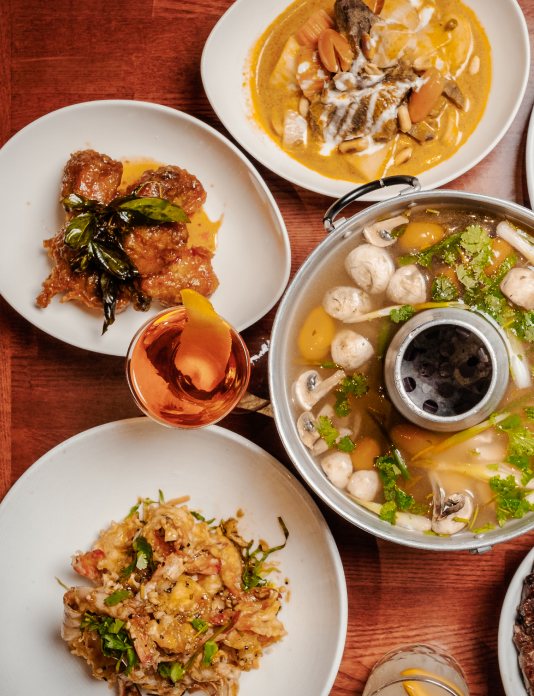 A table spread at Lotus of Siam: tom yum hotpot, curry, and fried chicken.