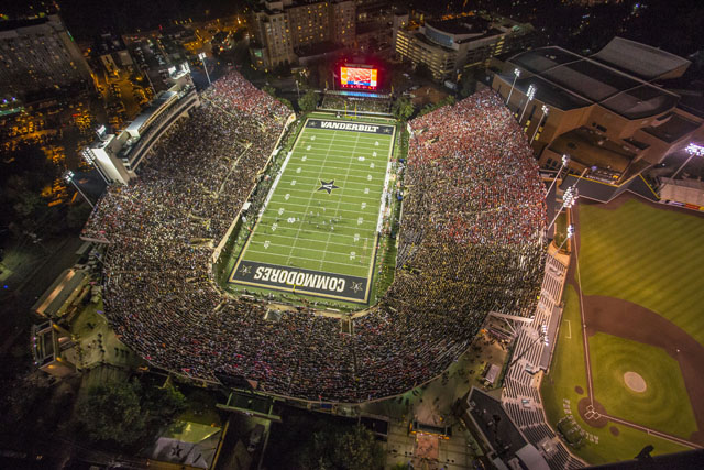 A packed college football stadium at night, seen from the air