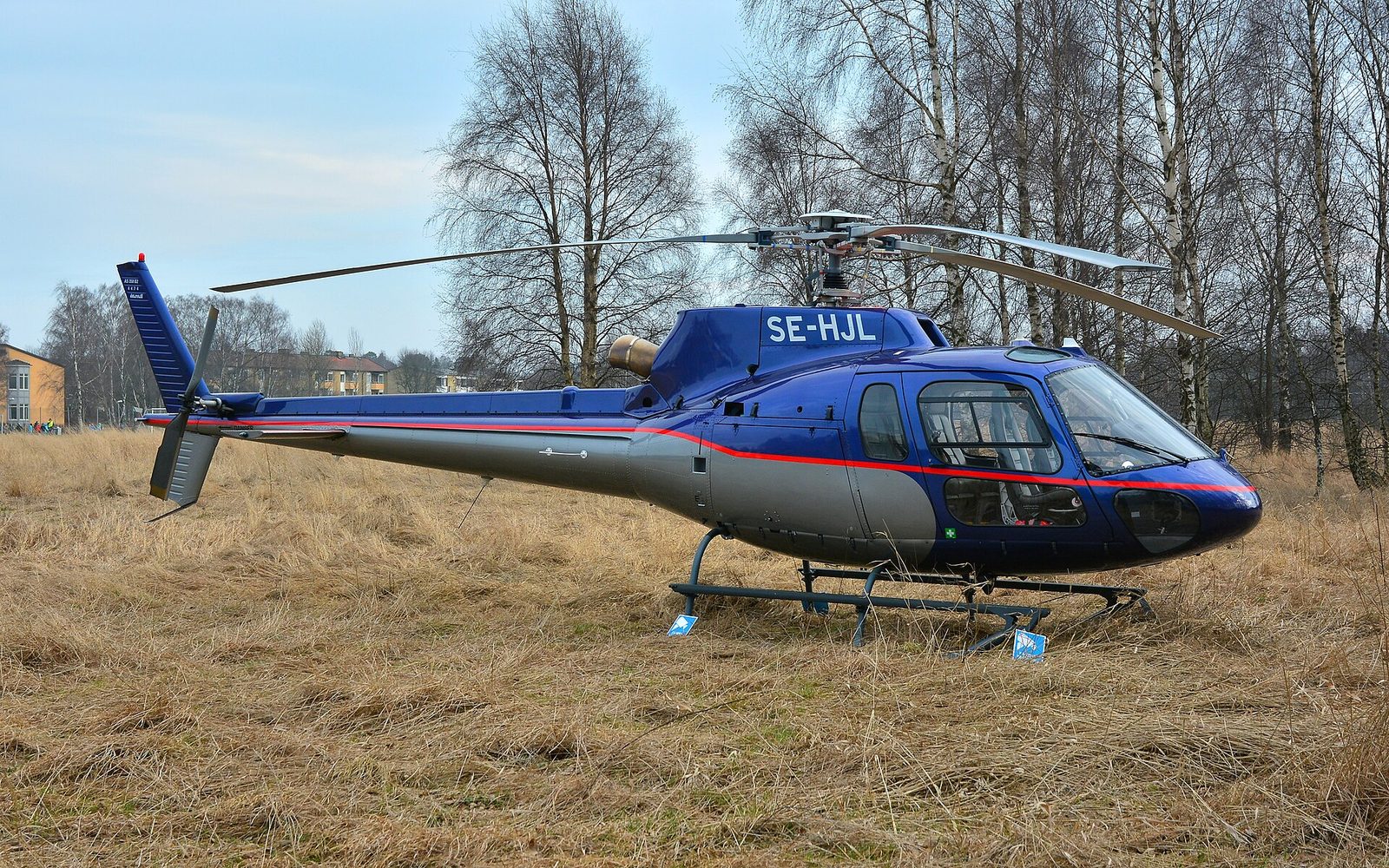 An Airbus H125/AS350 Ecureuil helicopter on the ground in daylight.