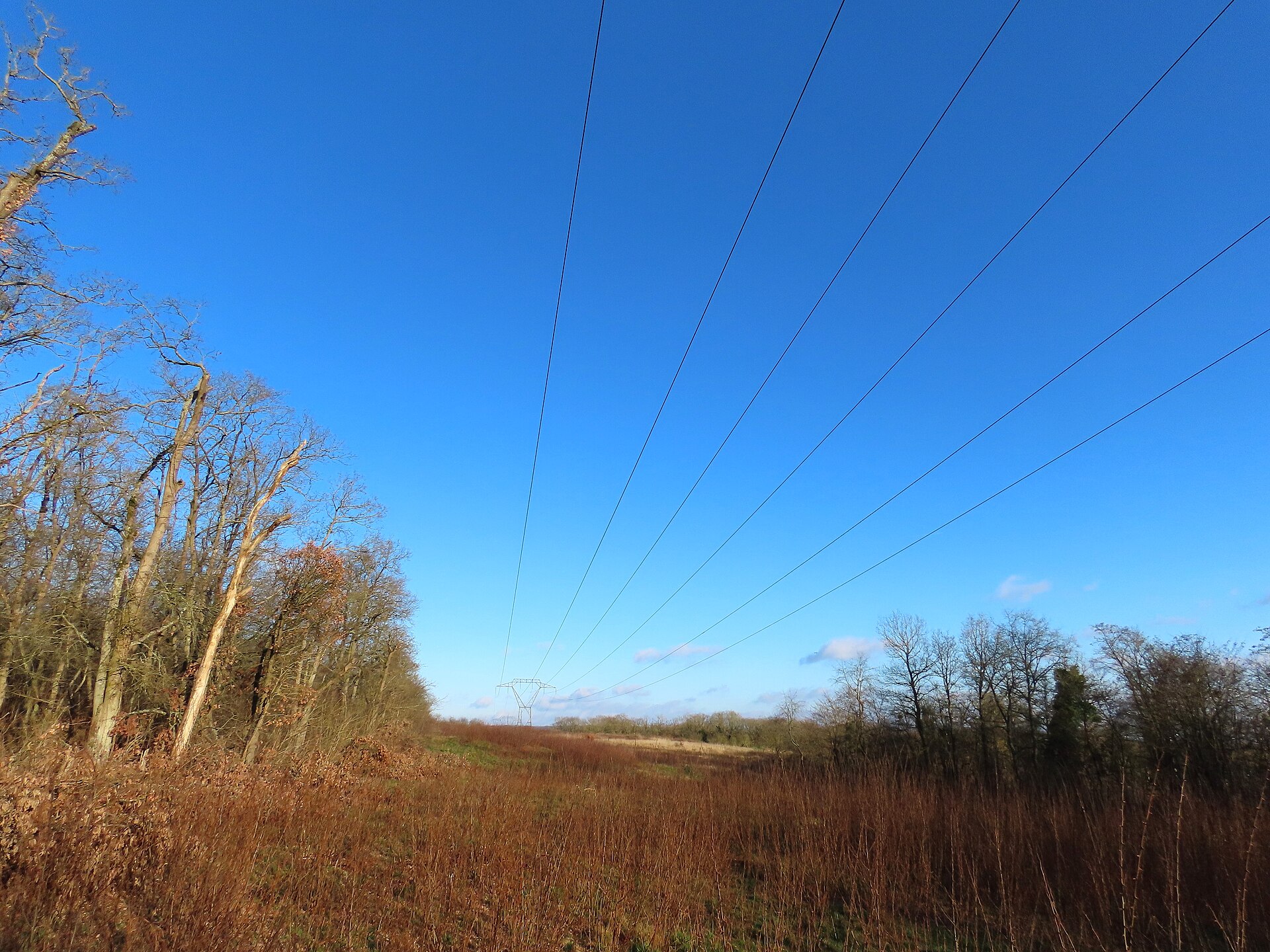 High-voltage transmission towers and power lines against a blue sky in France