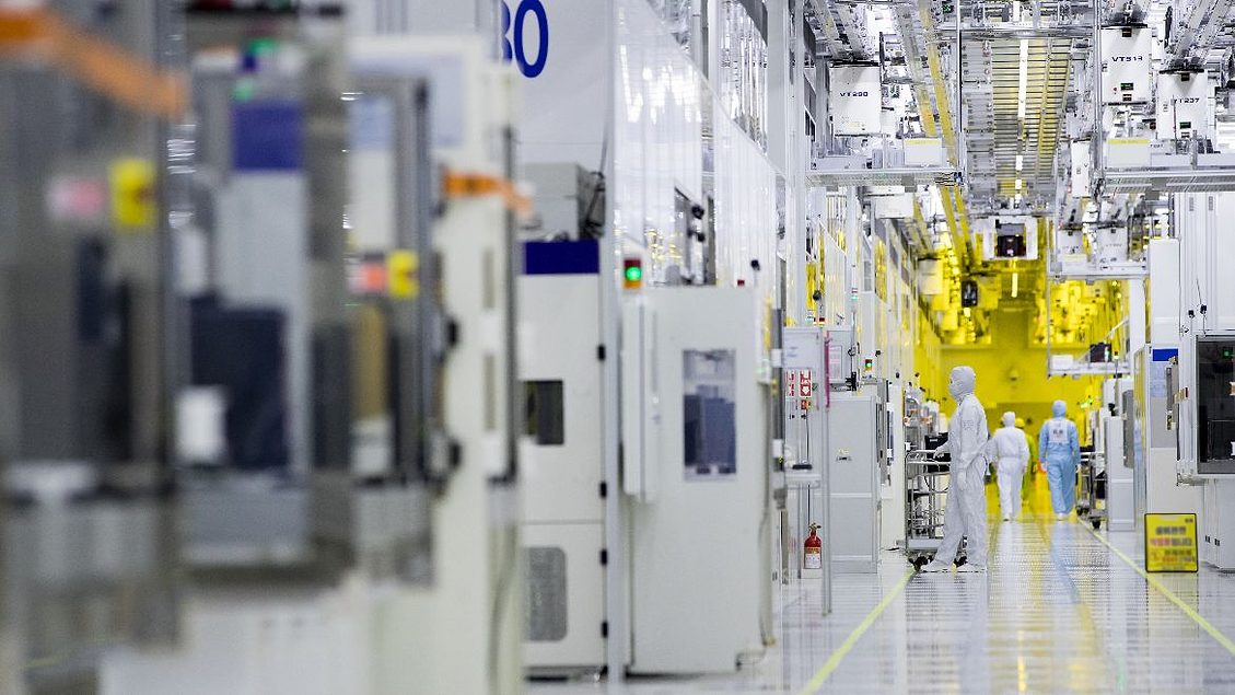 Engineers in protective suits inside a semiconductor fabrication plant
