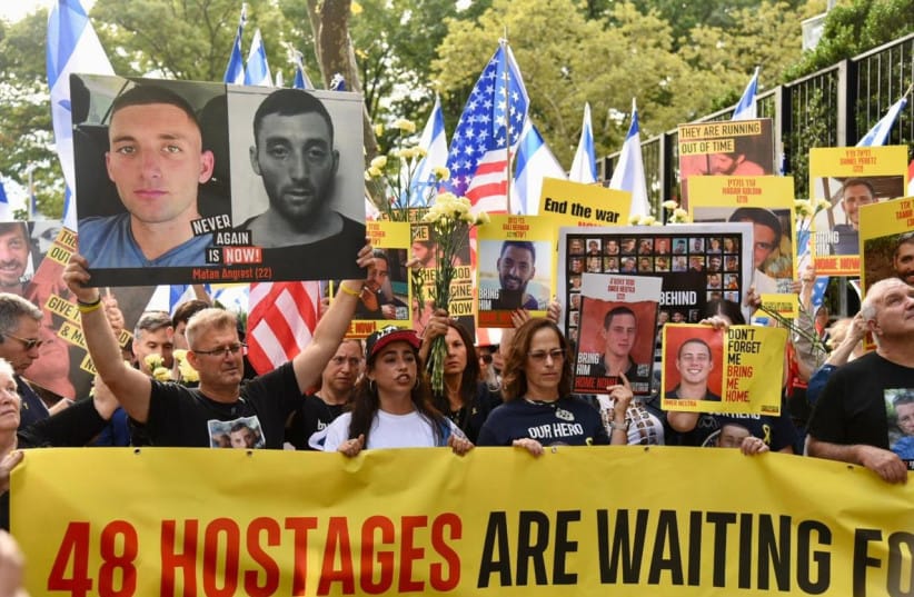 New Yorkers at an Oct. 7 anniversary commemoration holding hostage posters and a banner reading '48 hostages are waiting.'