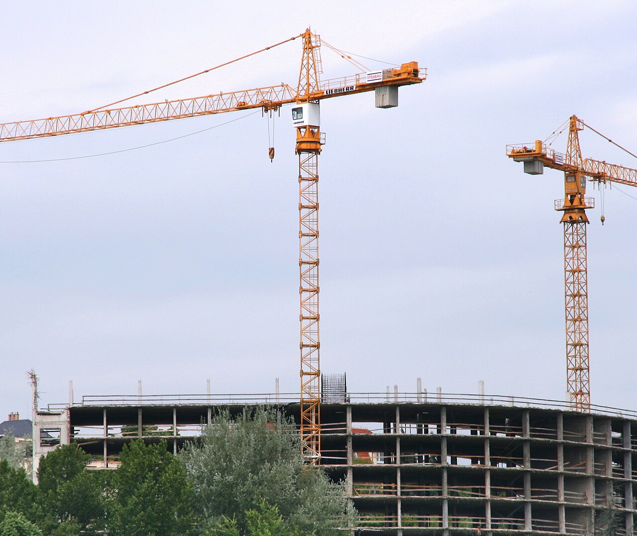 A bright daytime construction site with tower cranes and new apartment framing in Phoenix
