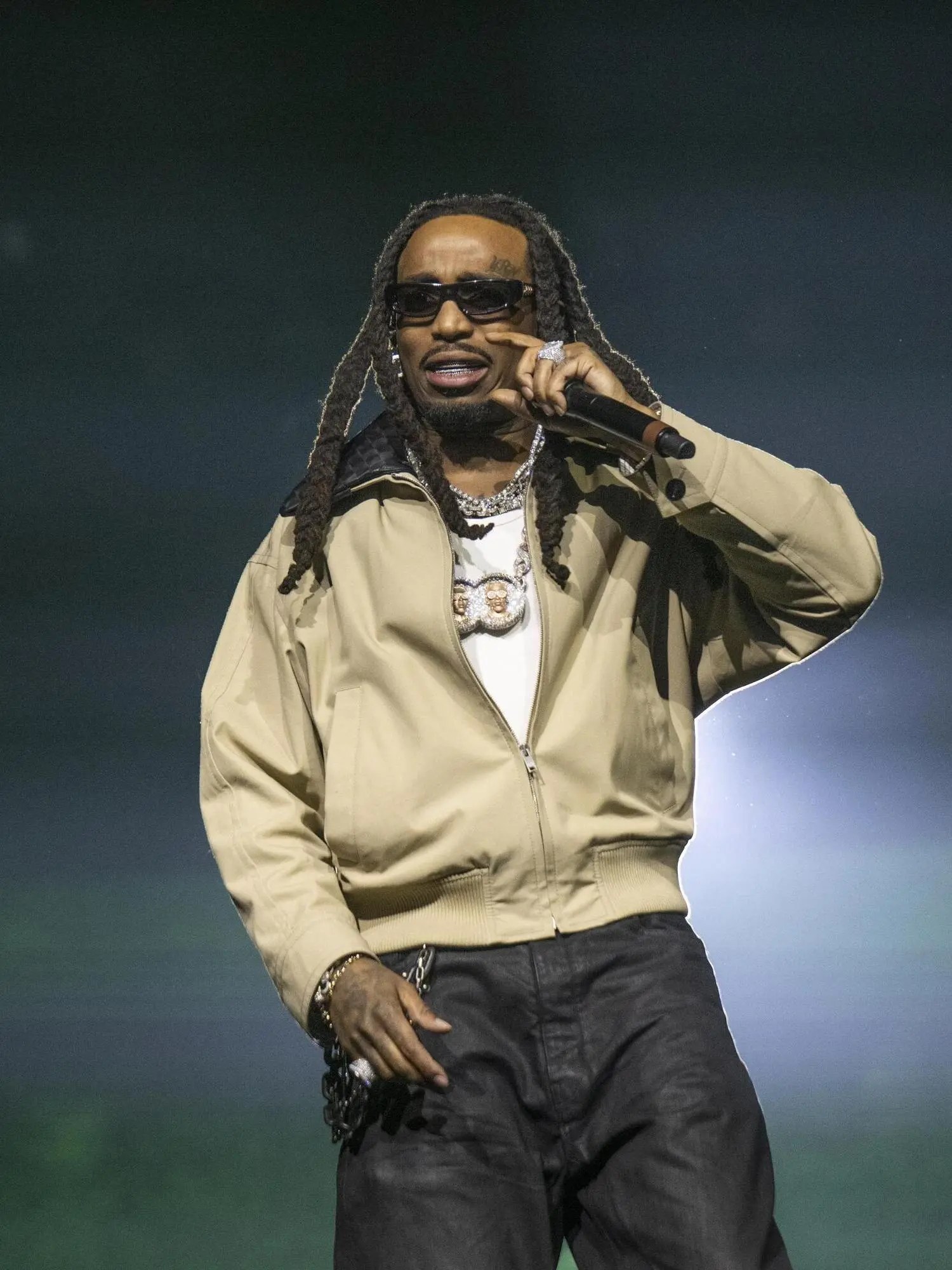 Quavo performing onstage with a microphone.