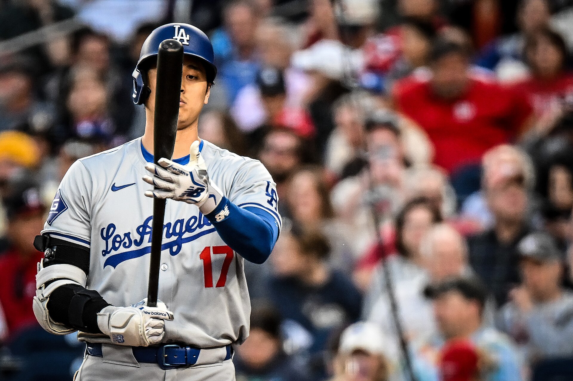 Shohei Ohtani holding his bat, watching the game from near home plate