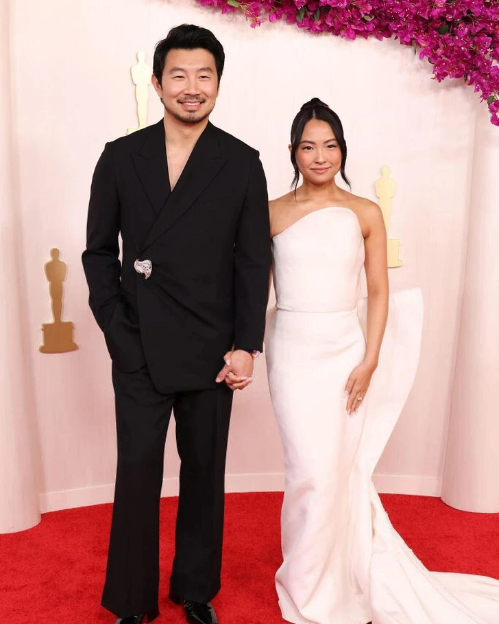 Allison Hsu, in a white strapless gown, walks the red carpet with Simu Liu at the Academy Awards.