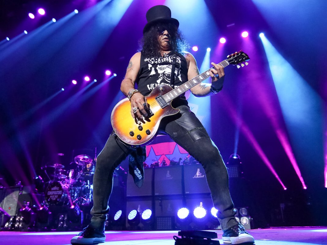 Slash playing a guitar solo under stage lights