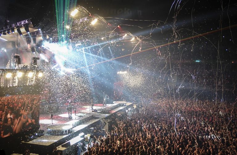 Rock concert crowd with raised hands under bright stage lights