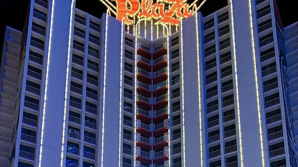 The Plaza Hotel & Casino tower lit up at night in downtown Las Vegas — the 2026 Slots Hall of Fame induction happens there today at 1 p.m.