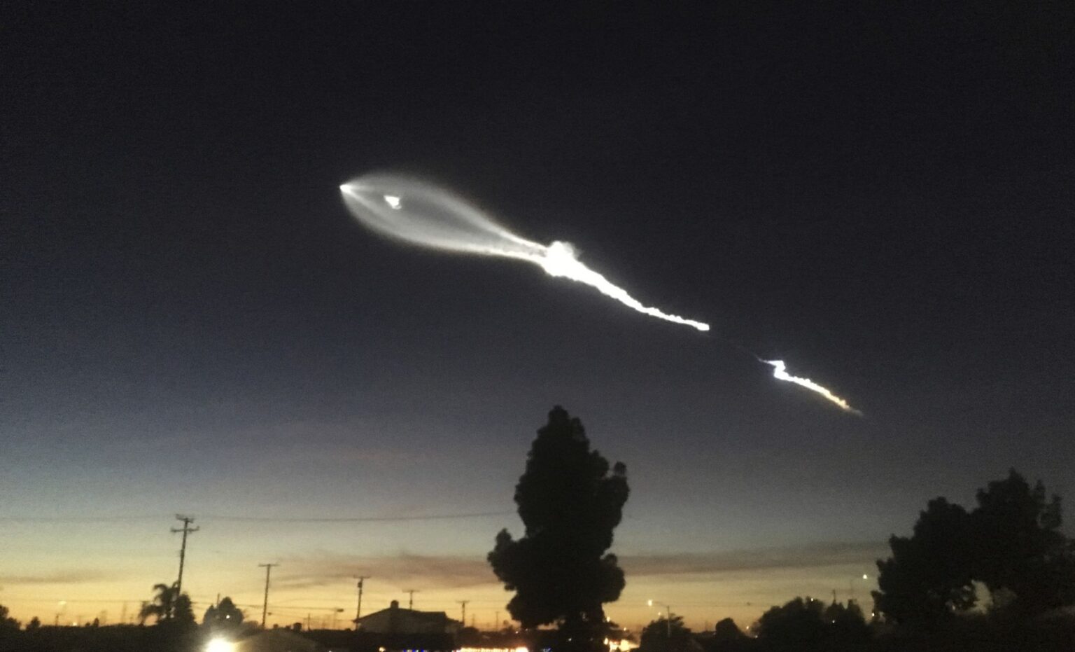A SpaceX Falcon 9 rocket trail glowing over the Southern California sky at night