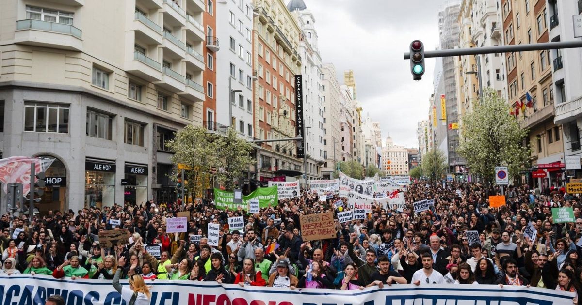 Demonstrators marching through a Madrid street with housing protest banners