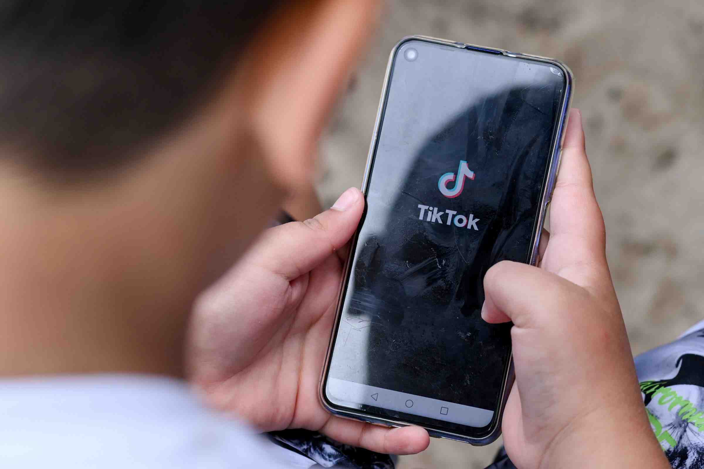A young user holding a smartphone with TikTok open