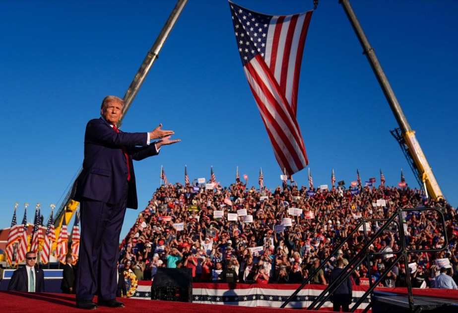 President Trump on stage at a campaign rally before a large crowd and American flags (file photo).