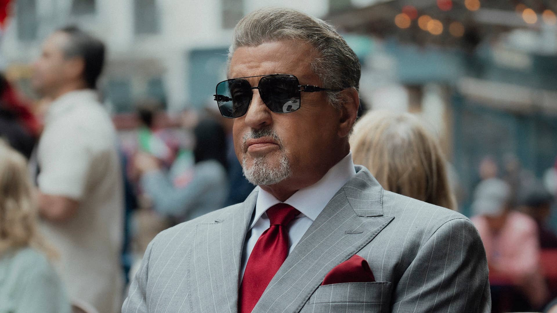 Sylvester Stallone as Dwight Manfredi in Tulsa King, in a gray pinstripe suit and sunglasses