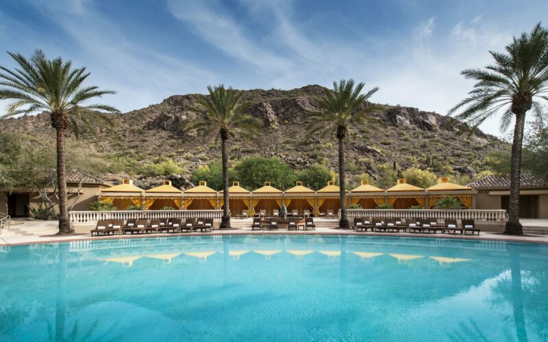 The Arizona Biltmore's resort pool with cabanas and palm trees against the desert hills