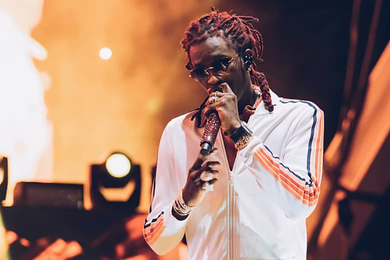 Young Thug performing on stage in a white tracksuit