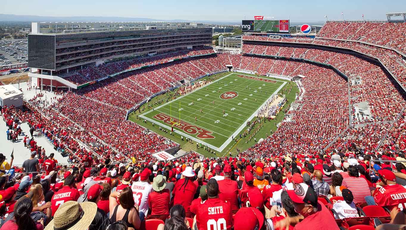 A packed NFL stadium glowing under the lights on game day