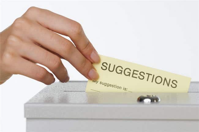 A hand dropping a suggestions card into a suggestion box